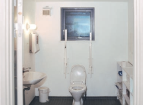 Badeværelse med hvide vægge og hvidt sanitet